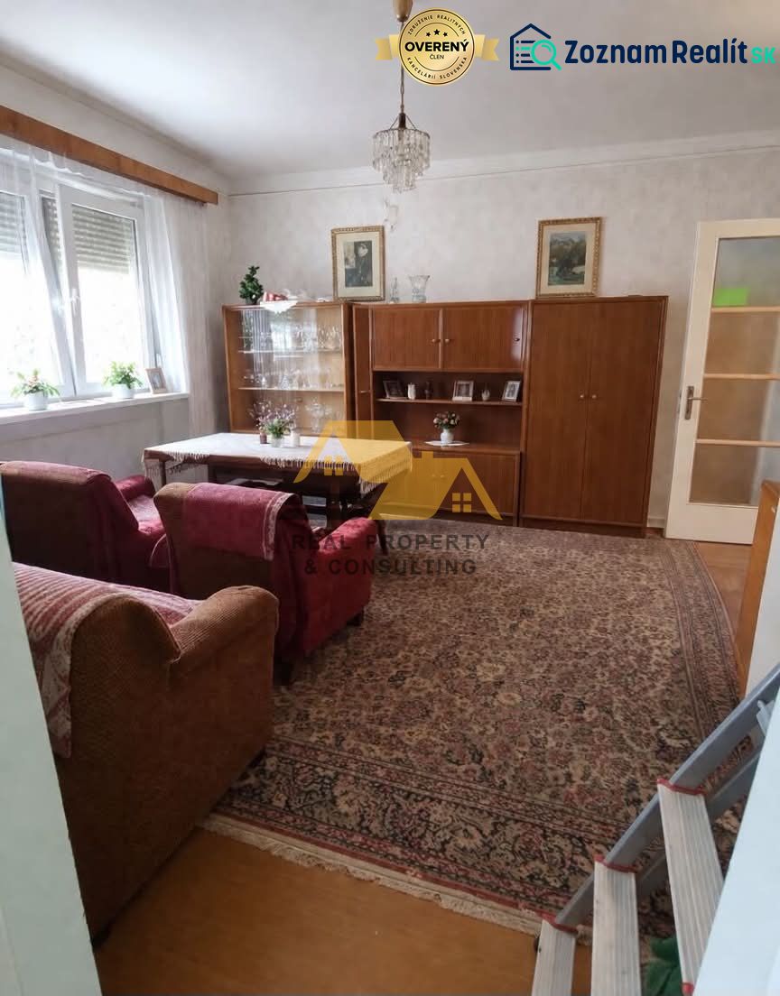 Nappali egy családi házban kanapéval, szekrénnyel és csillárral, fa dekorációjú padlóval.