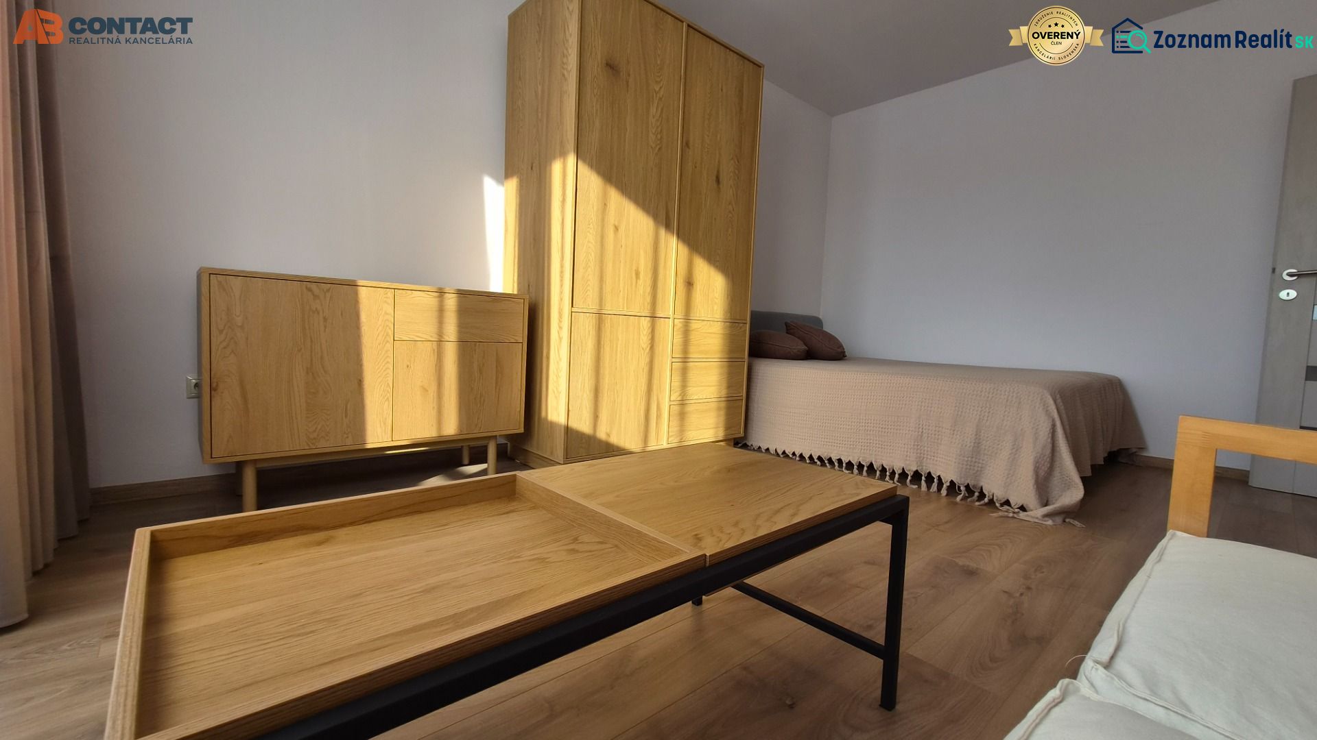1 szobás lakás belső tere ággyal, fa bútorokkal és fa dekorációjú padlóval.