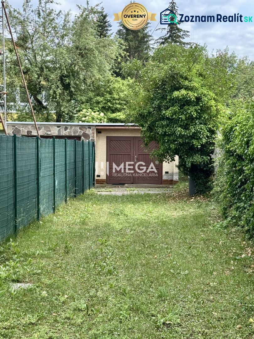 Garázs a Felszabadítók utcában, Homonnán, zölddel és kerítéssel körülvéve.