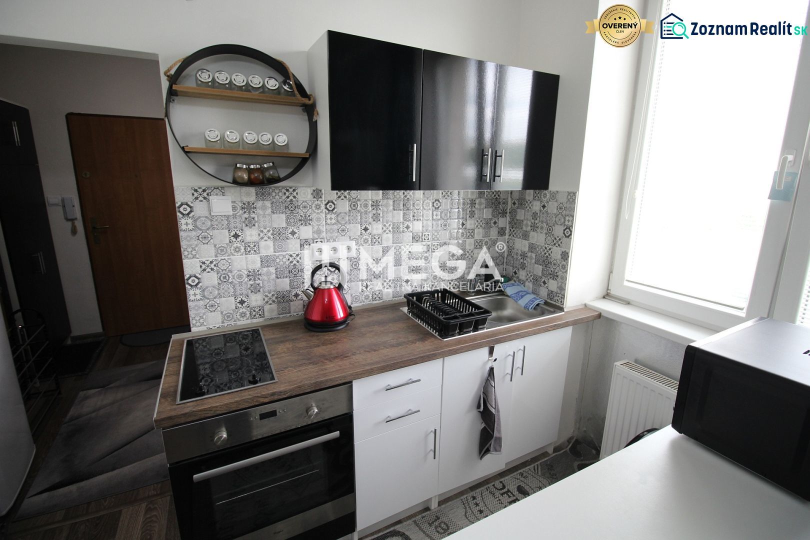 A nyaraló apartman konyhája fekete szekrényekkel, főzőlappal és dekoratív burkolattal.
