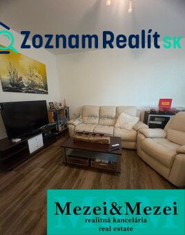 Nappali egy kétszobás lakásban fa dekor padlóval és kényelmes ülőgarnitúrával.