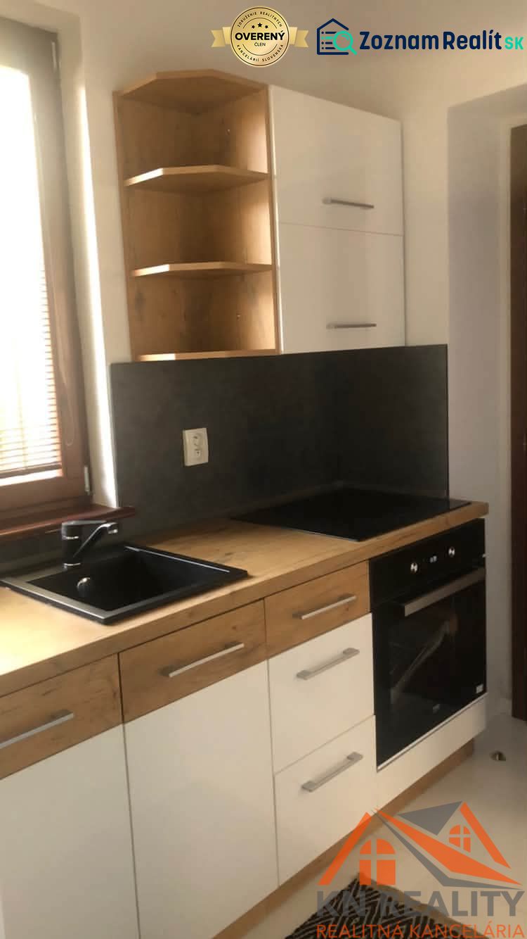 Konyhapult egy kétszobás lakásban fekete mosogatóval és fehér szekrényekkel.