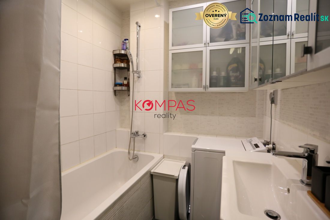 Kétszobás lakás fürdőszobája káddal, szekrényekkel és mosógéppel.