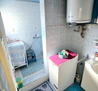 Kúpeľňa s umývadlom, ohrievačom a sprchovým kútom, vhodná pre rodinný dom.