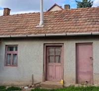 Na fotografii je vidieť starší rodinný dom s fialovými dverami, satelitnou anténou a plechovou garážou.