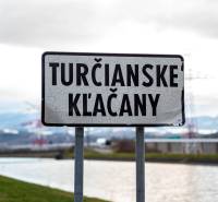 Ceduľa Turčianske Kľačany pri rieke, v pozadí hory a elektrické vedenie.
