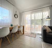 A nyaraló apartman világos nappalit kínál étkezőasztallal és kényelmes kanapéval.