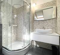 Fürdőszoba egy üdülő apartmanban modern zuhanyzóval és mosdóval.