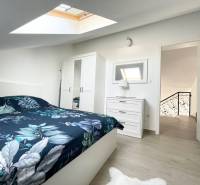 Hálószoba egy üdülő apartmanban ággyal, szekrénnyel és tetőablakkal.