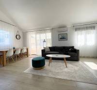 Tágas nappali rekreációs apartman kényelmes ülőgarnitúrával és étkezőasztallal.