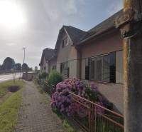 Családi ház Harkócon kőjárdával és virágzó hortenziákkal a kertben.