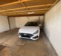 A garázs belseje egy fehér Hyundai márkájú autóval, amely bent van leparkolva.