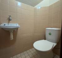 WC mosdókagylóval egy családi házban, bézs csempével burkolva.