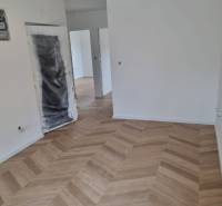 Négy szobás lakás részben befejezett területe, ahol fa padló van lerakva.