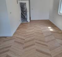 Négy szobás lakás belső tere új fa padlóval és ablakból érkező világítással.