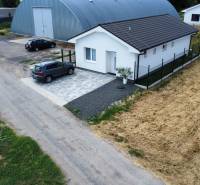 Családi ház Nižnában aszfaltos úttal és parkoló autóval.