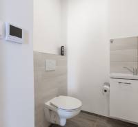 WC és mosdó egy családi házban fehér falakkal és világos csempékkel.