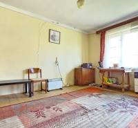 Szoba szőnyegekkel, régi bútorokkal és ablakokkal, repedésekkel a falakon. Ingatlanok - lakhatás.