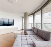 Nappali egy négyszobás lakásban kanapéval, televízióval és panorámás kilátással a folyóra.