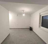 Üres szoba egy négy szobás lakásban fehér falakkal és szürke padlóval.