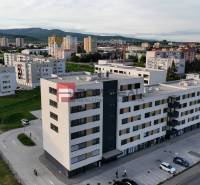 Kereskedelmi helyiségek a pezinki Obchodná utcában, lakóházakkal és zöldterületekkel körülvéve.