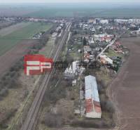 Vasútvonal mezők és házak által körülvéve, a Partizánska utcán, raktárak és csarnokok láthatók.