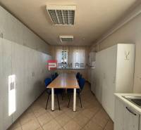 A gyártóhelyiség belső tere hosszú asztallal és szekrényekkel, egyszerű berendezés.