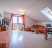 Nyaraló apartman narancssárga kanapéval és étkezőasztallal a tetőablak alatt.