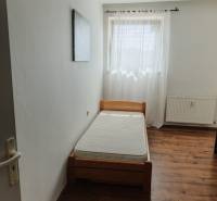 Egyszemélyes ágy egy szobában ablakkal és függönnyel egy kétszobás lakásban.