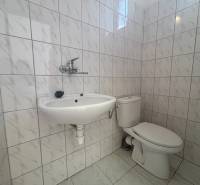 Fürdőszobai helyiségek fehér csempékkel, mosdóval és WC-vel a raktárakban és csarnokokban.
