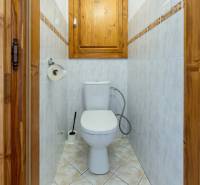 WC egy 3 szobás lakásban kerámia burkolattal és tárolószekrénnyel.