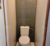 Fehér márvány padlóburkolattal ellátott WC egy kétszobás lakásban.