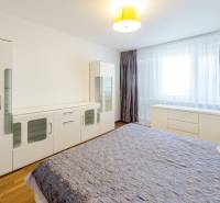 Világos hálószoba nagy ággyal, komóddal és ruhásszekrénnyel egy háromszobás lakásban.