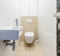 Fürdőszoba egy háromszobás lakásban WC-vel, mosdóval és dekoratív ajtókkal.