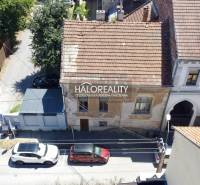 Családi ház Rimaszombatban régi homlokzattal és az utcán parkoló autókkal.