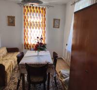 Ebédlő egy családi házban, asztallal, székekkel, virágokkal, szőnyeggel és függönnyel.