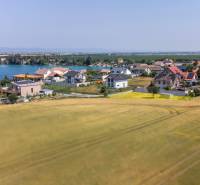 Telkek - lakóövezet Dunajská Lužná-ban, kilátással a tóra, házak és mező.