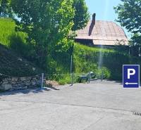 Donovaly utcai parkoló Donovaly városában, családi házak mellett, fákkal és fűvel.