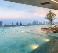 Medence napozóágyakkal és kilátással Pattaya város panorámájára, lakásépítések.