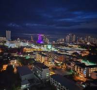 Éjszakai kilátás Pattaya városára, megvilágított épületekkel és sziluettekkel a horizonton.