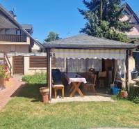 A Szenci Nyaraló kertje pavilonnal, paddal és növényekkel teli virágládákkal.