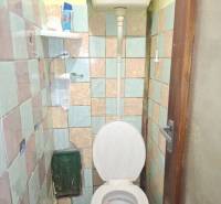 Egyszerű fürdőszoba egy családi házban régebbi WC-vel és csempékkel.