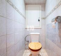 WC csempékkel a háromszobás lakásban, fa ülőke, papírtartó.