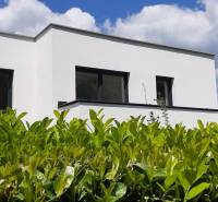 Fehér homlokzatú villa Hainburg an der Donau-ban, zölddel körülvéve a kék ég alatt.