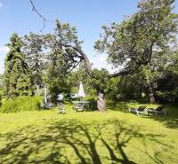 Egy villa kertje Hainburg an der Donau-ban gyepfelülettel, fákkal és kerti ülőhellyel.