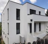 Villa fehér homlokzattal Hainburg an der Donau-ban, zölddel és kék éggel körülvéve.
