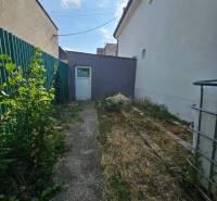 Családi ház Nagymácsédon, a Rybničná utcában, keskeny udvar zölddel és beton járdával.