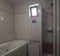 Fürdőszoba családi házban csempével, káddal és zuhanyzóval.