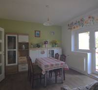 Családi ház ebédlője asztallal, székekkel és díszekkel ellátott szekrénnyel.