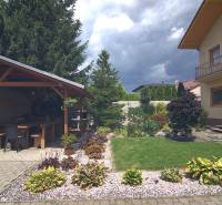 A Sport utcai családi ház kertje Brodskóban, pavilonnal és virágágyásokkal.